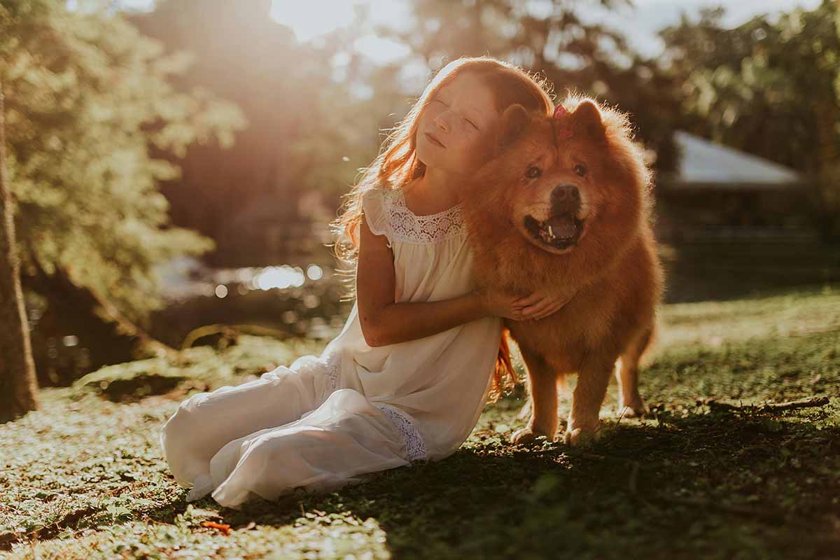 a dog and girls stand in the filed.