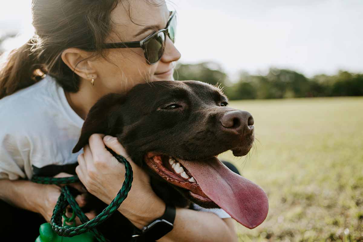 a girl wearing glasses is standing on dog's neck.